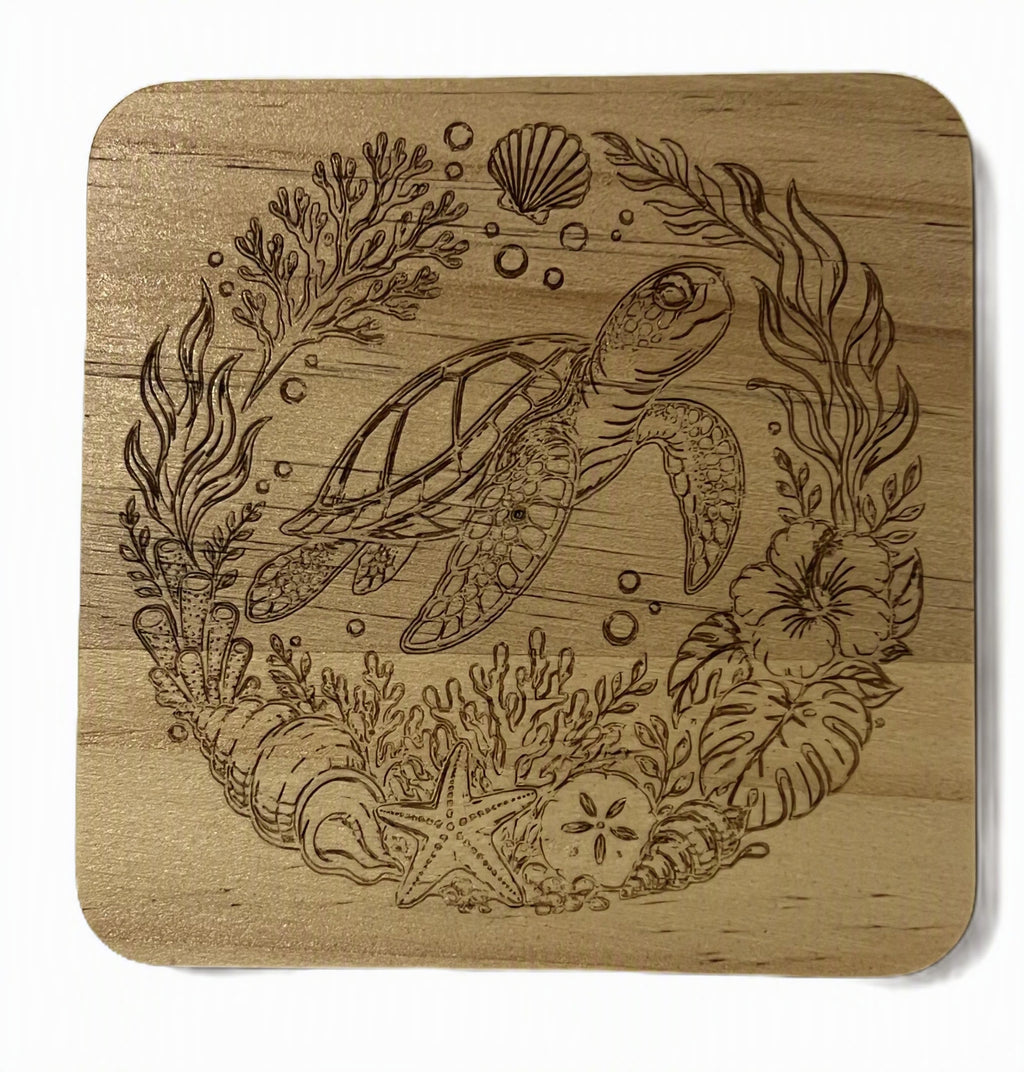 A square wooden coaster with rounded corners featuring a laser-engraved design of a sea turtle surrounded by marine plants, coral, bubbles, and a starfish.