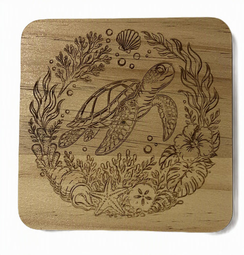 A square wooden coaster with rounded corners featuring a laser-engraved design of a sea turtle surrounded by marine plants, coral, bubbles, and a starfish.