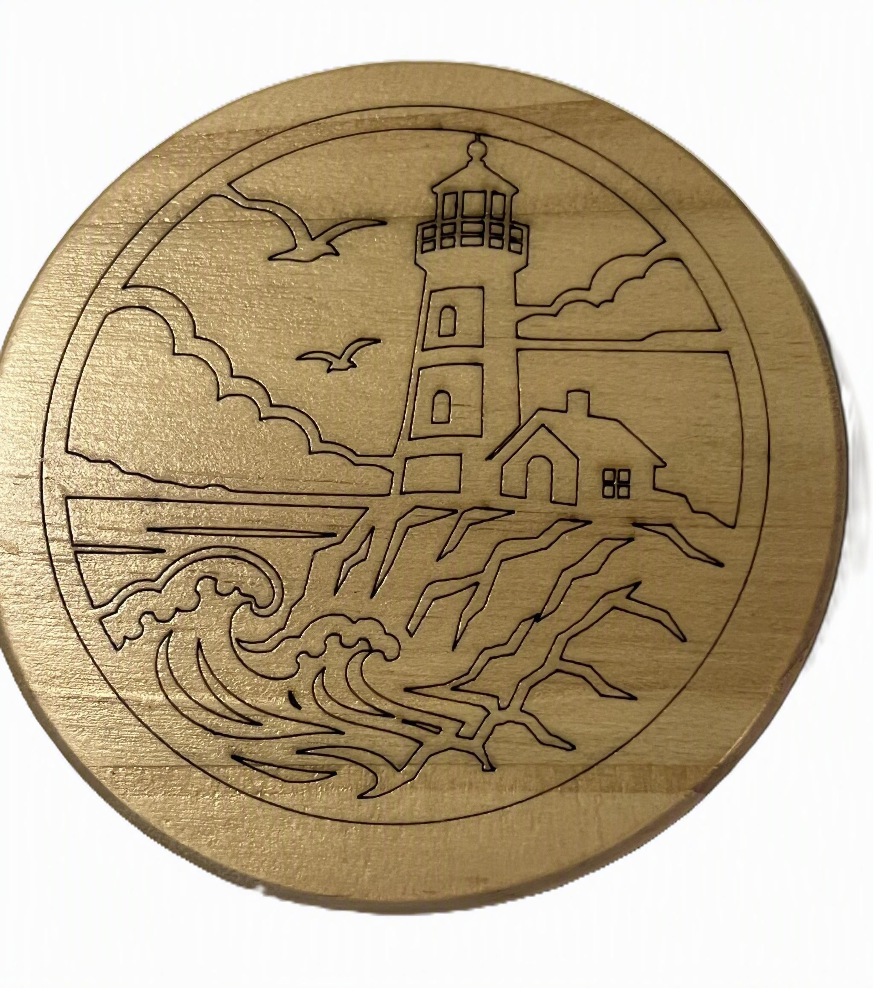 A round wooden coaster featuring an engraved lighthouse and coastal scene with waves, clouds, and birds.