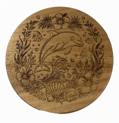 A round wooden coaster featuring a laser-engraved underwater scene with a dolphin, seashells, tropical flowers, and sea plants.