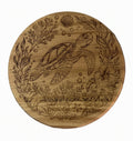 A round wooden coast plate engraved with an underwater scene featuring a sea turtle, seaweed, bubbles, and a shell.